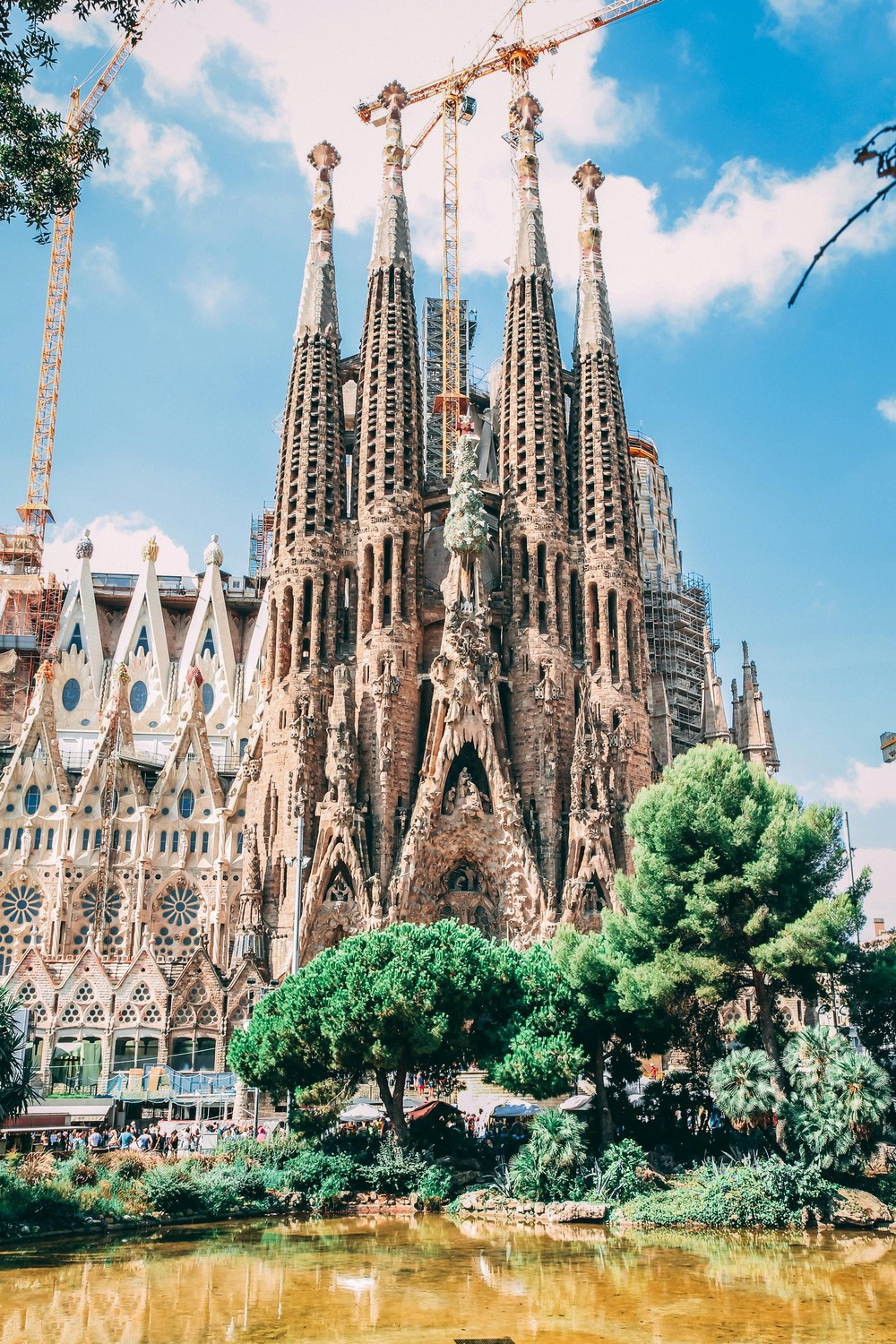 Sagrada Familia cathedral facade surrounded by green trees in Barcelona, Spain