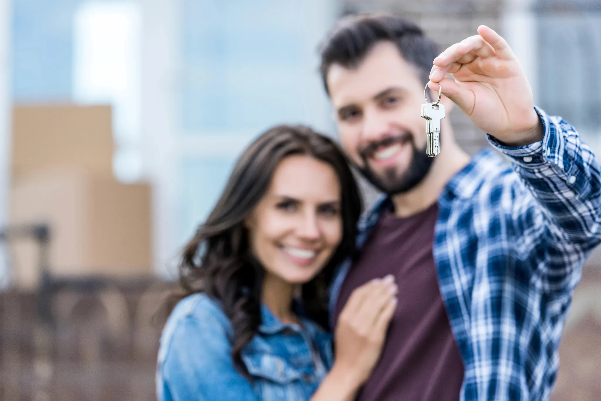 A smiling couple with the man holding up house keys.