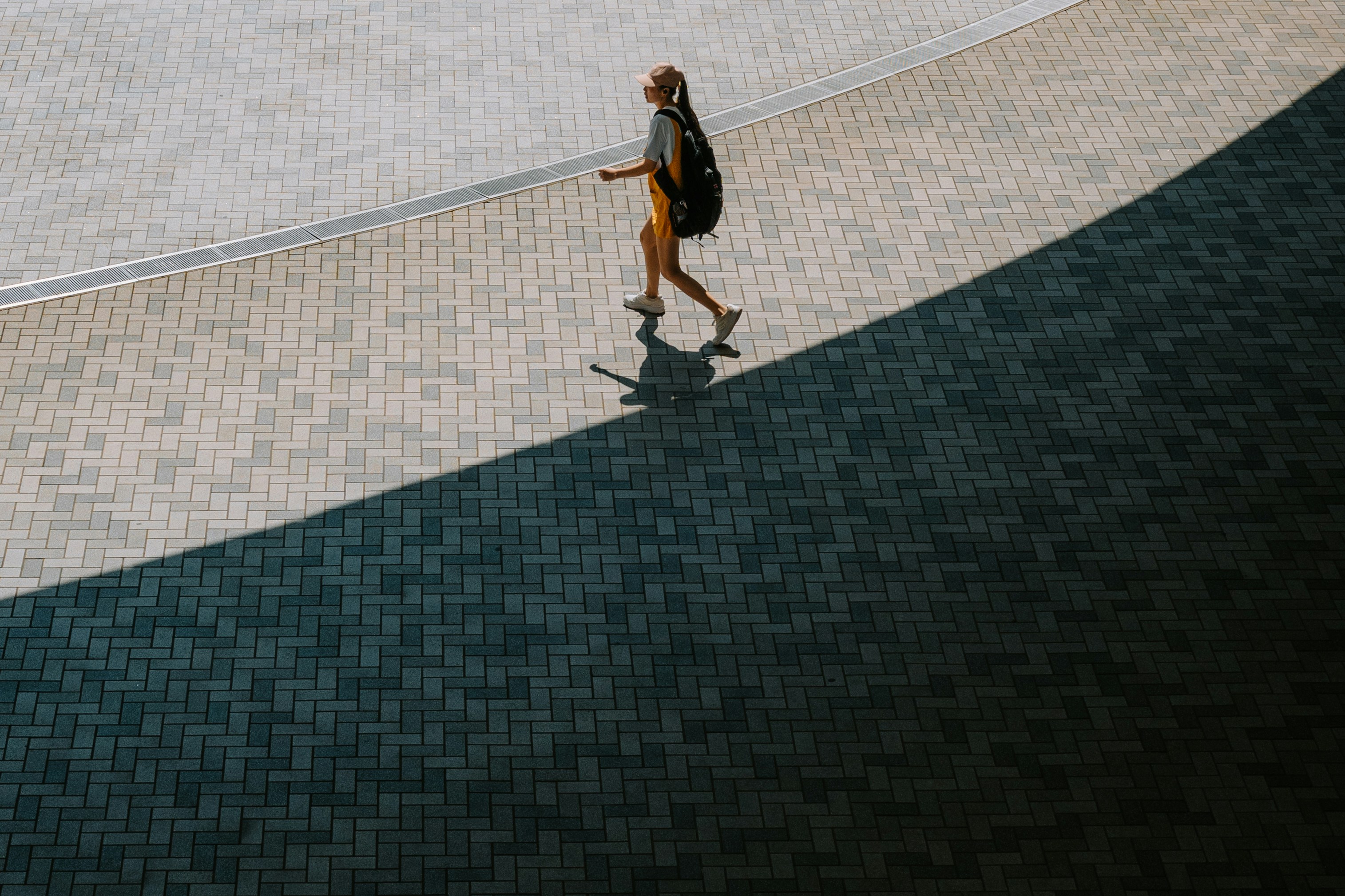 Woman walking on a curved pavement with shadow.