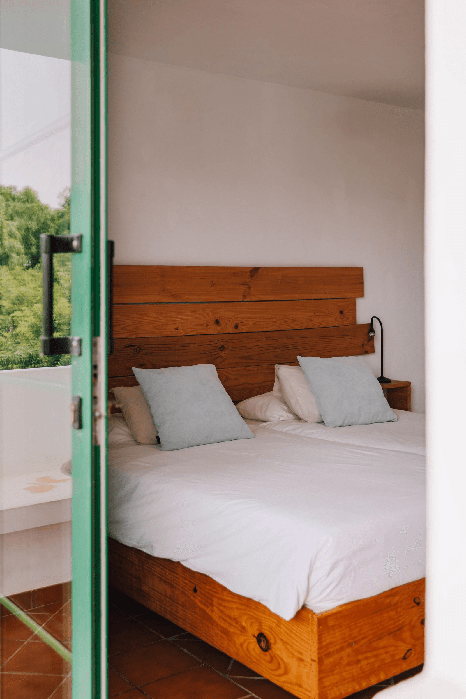 Dormitorio con cama de madera y almohadas azul claro.