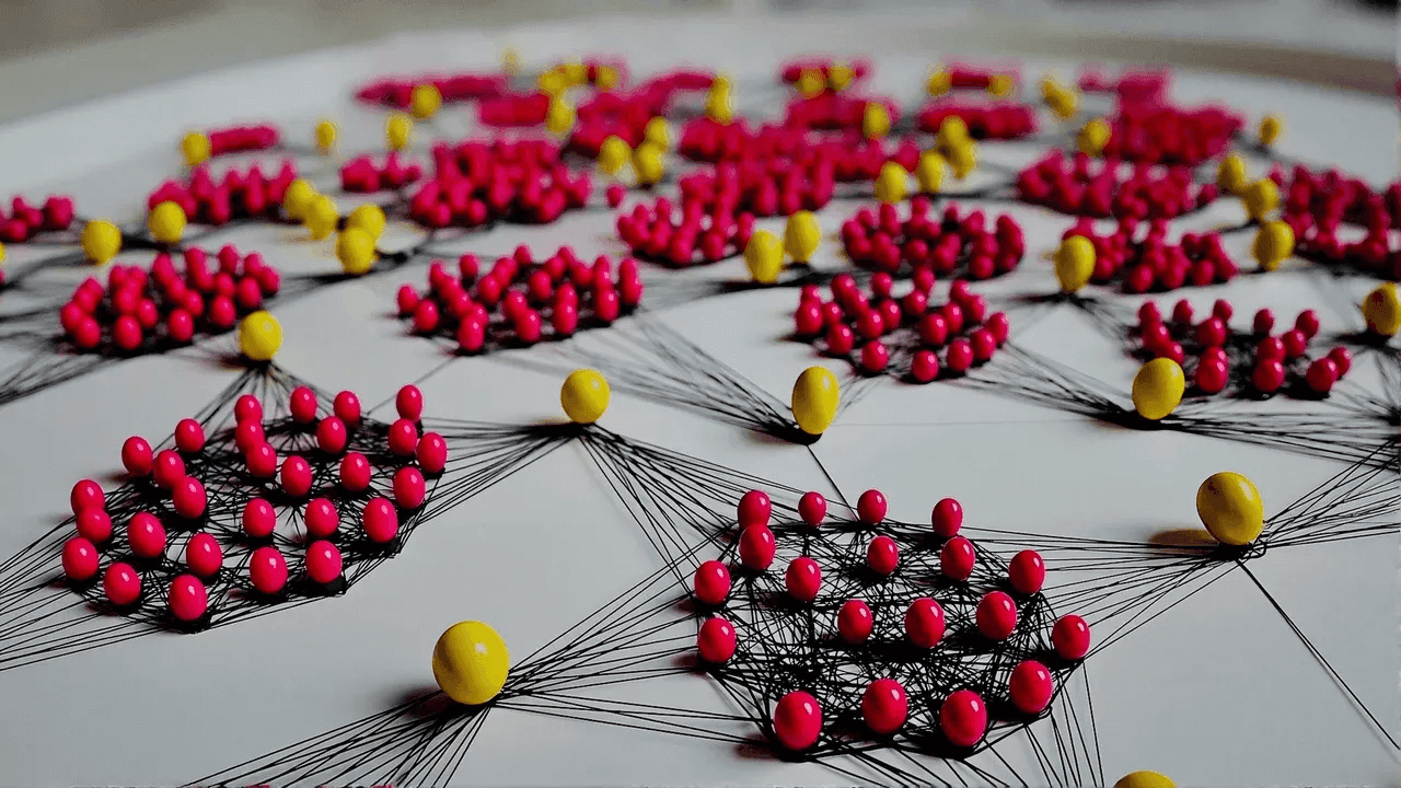 Network model of red and yellow nodes connected by black threads, showing clustered relationships