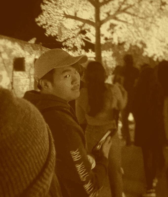 Photo of Evan Saisenesouk holding a Canon XSI Rebel camera in an outdoor garden in Madrid