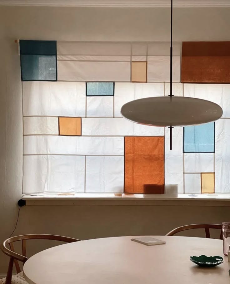This may contain: a white table and chairs in front of a window with multicolored squares on it