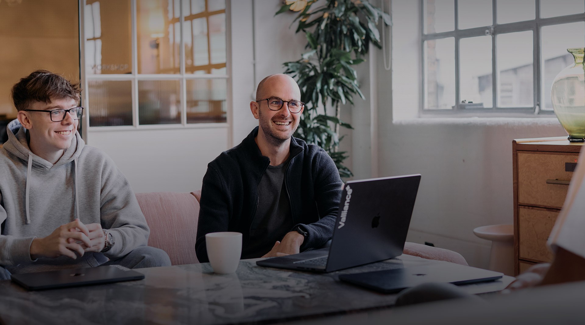 Header image for Valliance Join Us Section. The image has 3 colleagues looking happy informally chatting in a relaxed open office environment