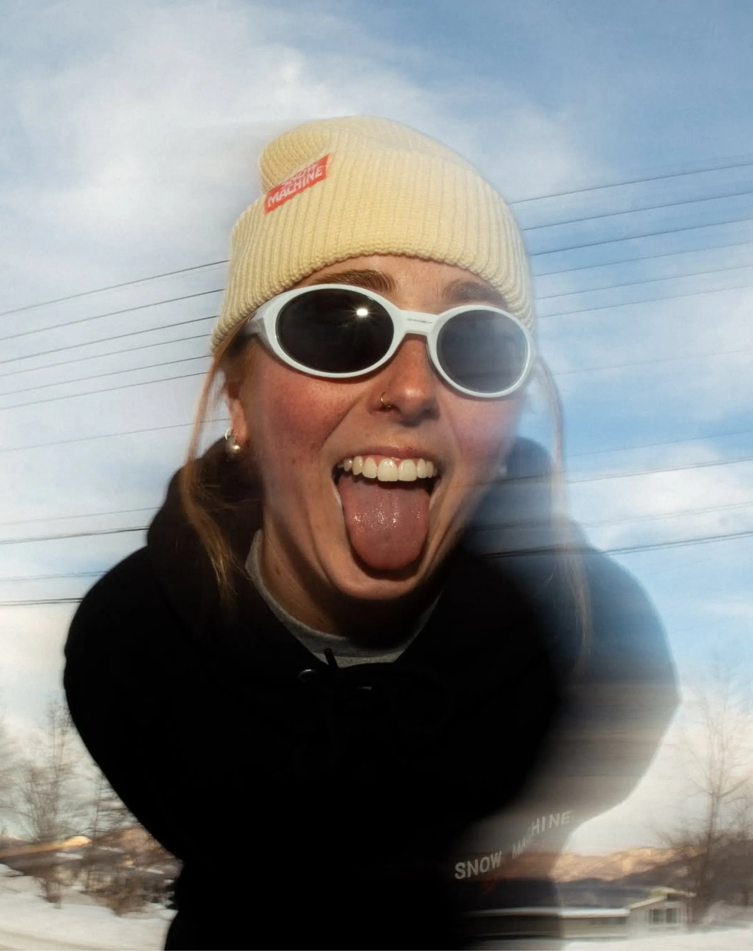 A festival-goer wearing a Snow Machine branded beanie and sunglasses