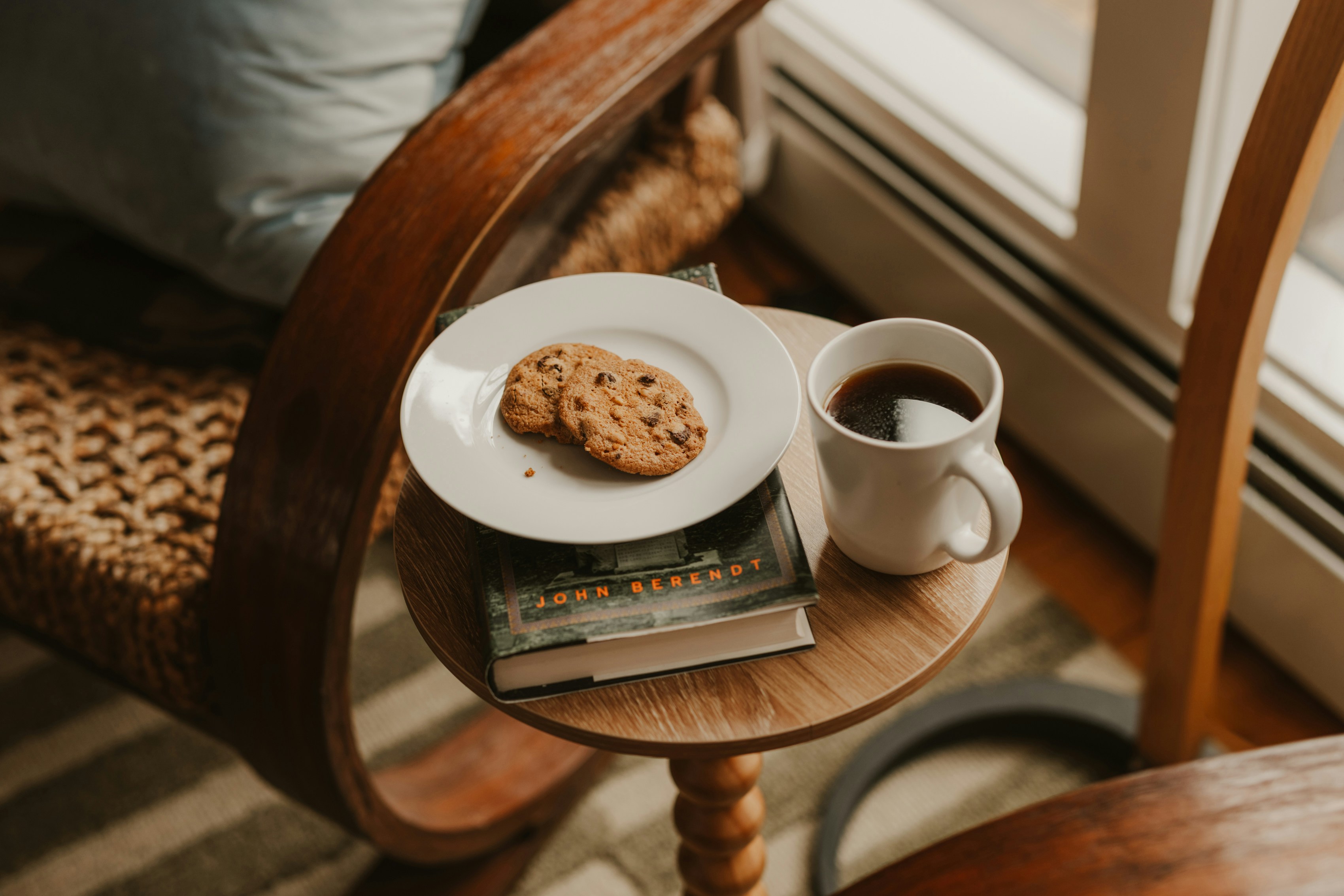 Coffee and cookies on a small table next to chair