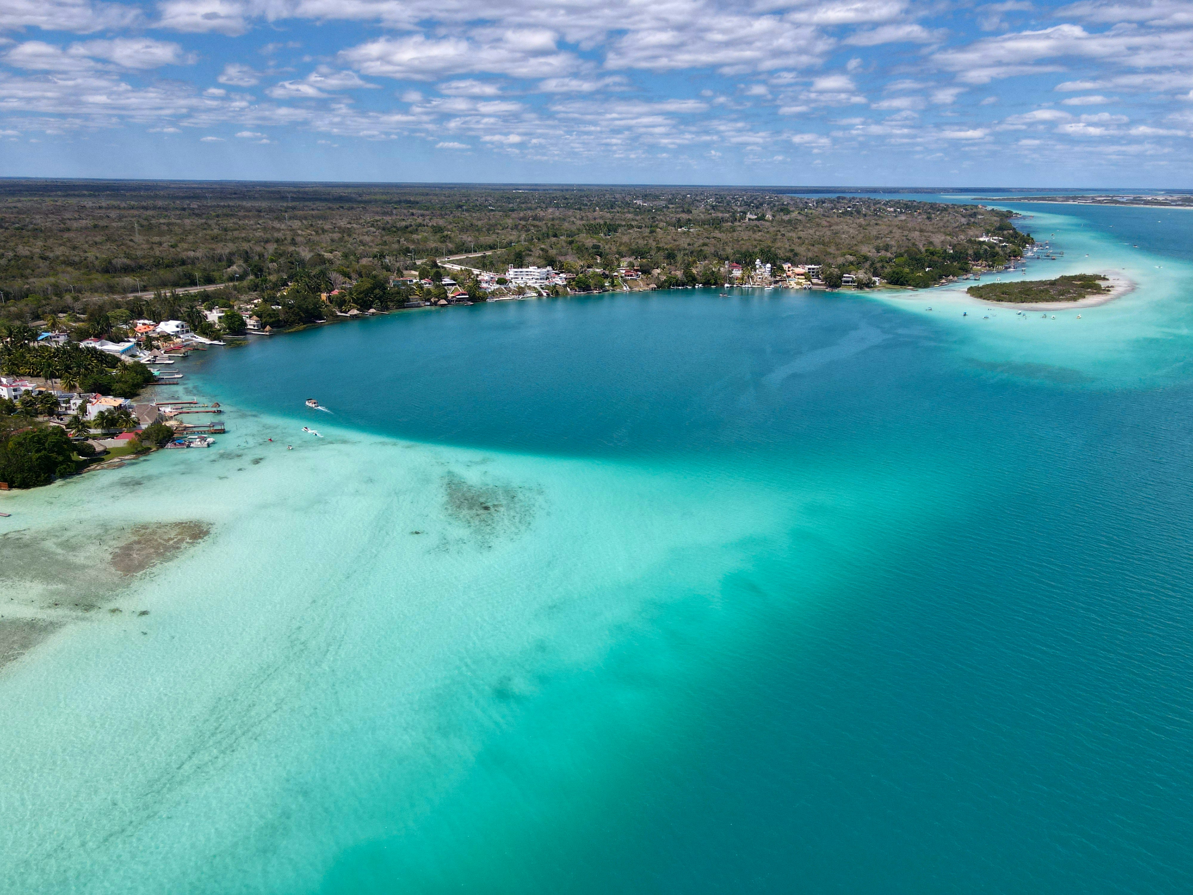 a large body of water with a beach and houses in the background