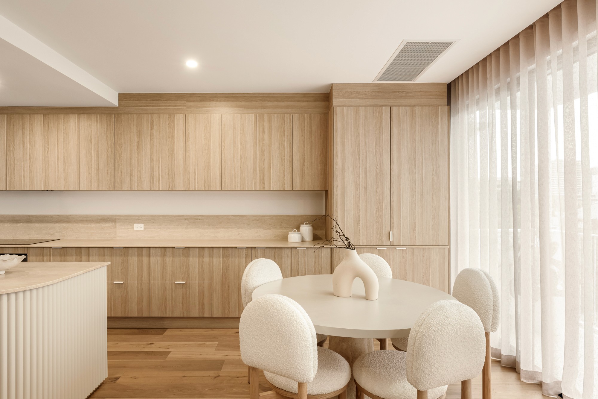  Dining area with sheer curtains, a round dining table and warm neutral tones.