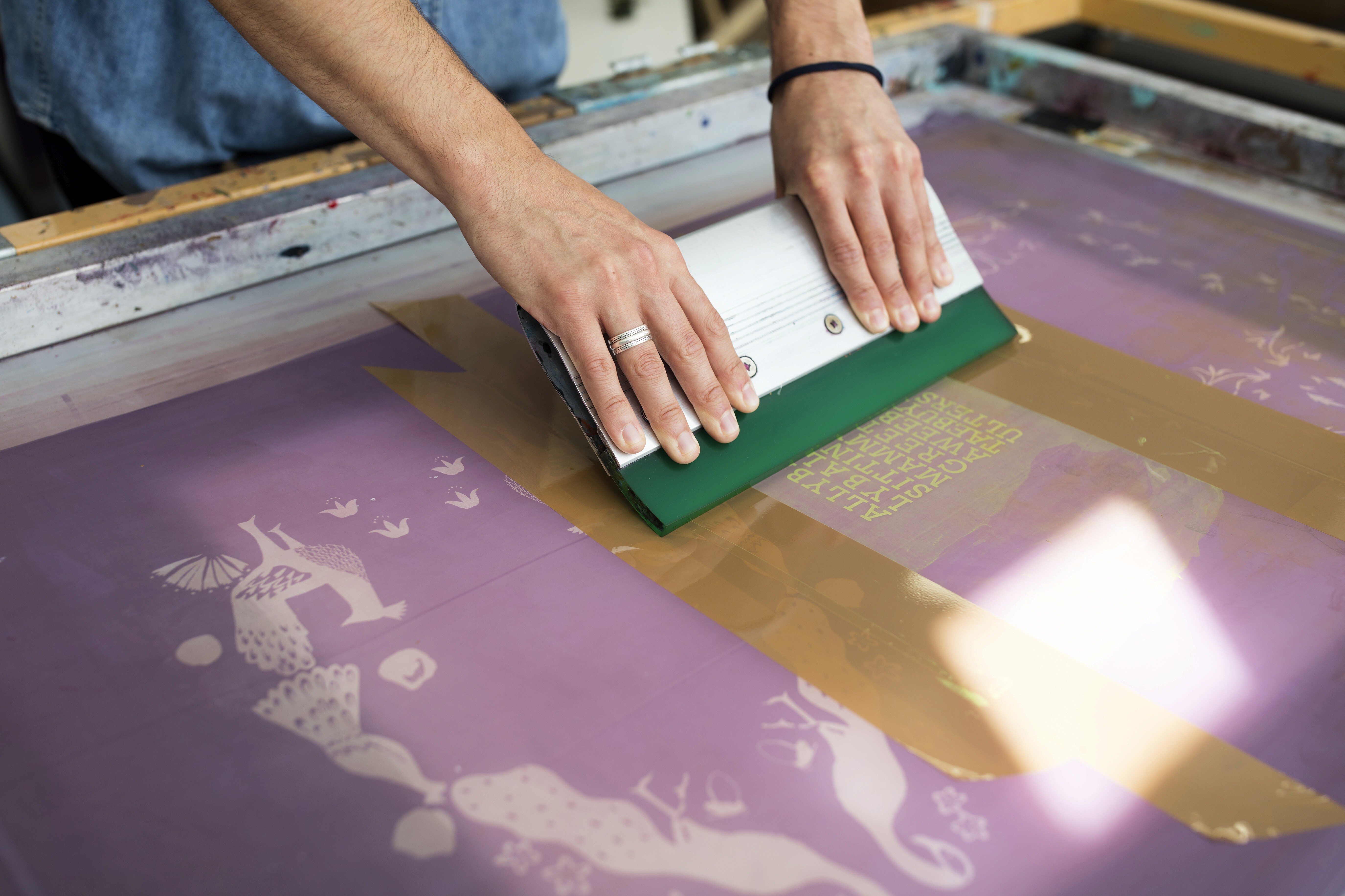 Proceso de serigrafía artesanal con rasqueta sobre pantalla — taller BarcelonaImg 4 — Camiseta azul doblada o empaquetada: Camiseta personalizada terminada lista para entregar — producción textil Divuit Studio Barcelona