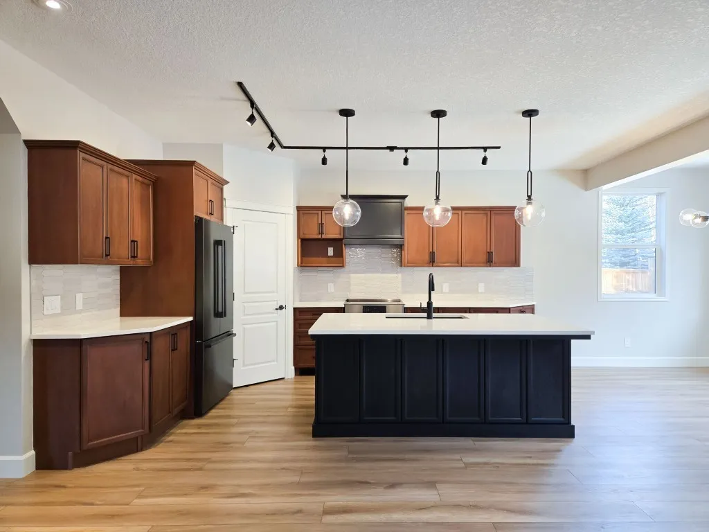 Image of Modern kitchen design with island, pendant lighting, and dark wood cabinets by KHD Homes.