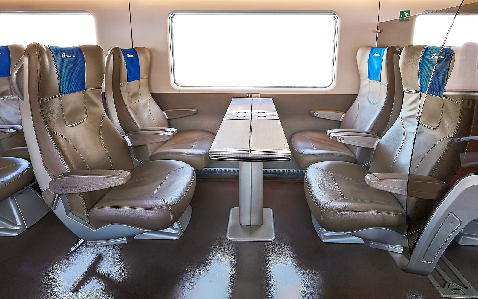 Trenitalia business class seats with table in train interior.
