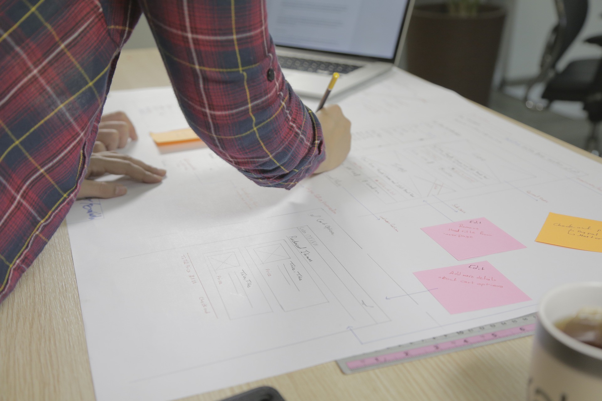 Designer sketching interface wireframes on large sheets with sticky notes