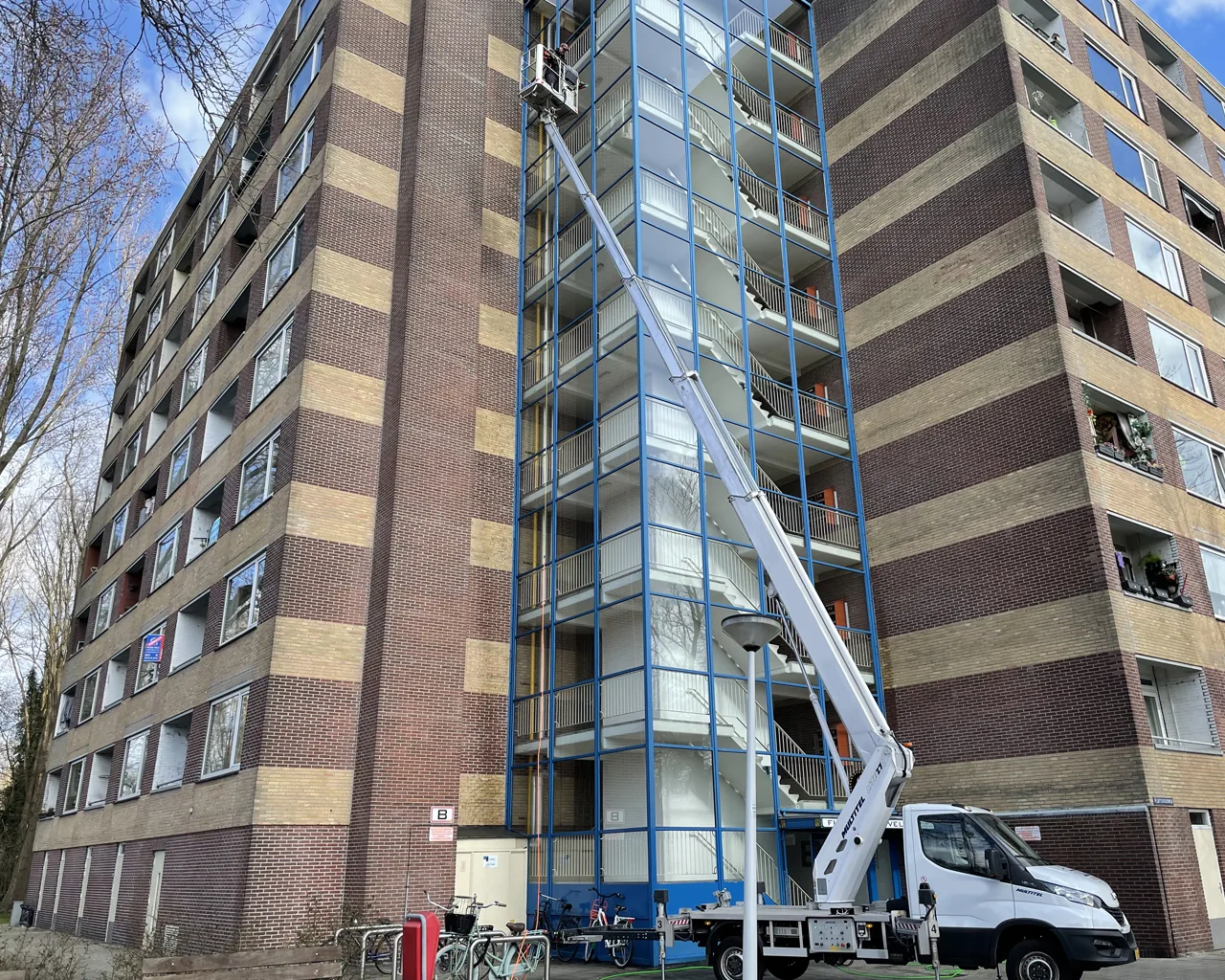Hoogwerker van Qlean Facility Group bij een VvE-appartementencomplex voor glasbewassing en gevelonderhoud