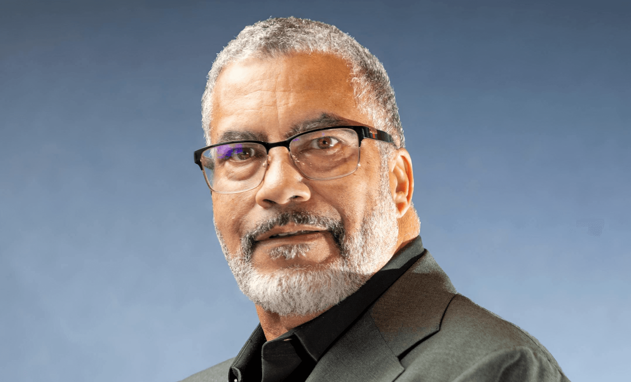 man wearing glasses in front of grey background