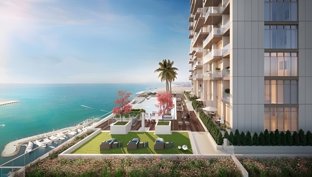 Anwa Omniyat tower at sunset, viewed from the water, with vibrant colors illuminating the sky and its reflection.