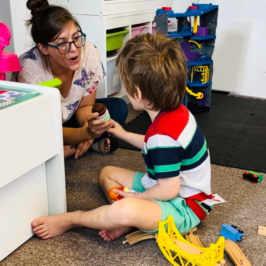 A child and Horizon Hub team member are playing with wooden toys in a classroom