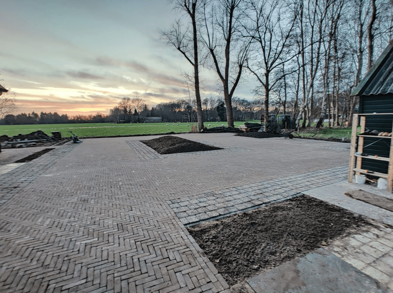 Nieuw aangelegd ruim tuinterras met bakstenen bestrating bij landelijk uitzicht in Friesland