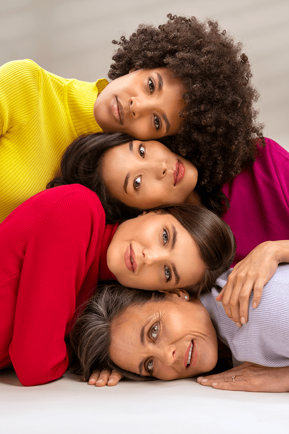 Group portrait of diverse female Croma models of different ages, lying close together indoors
