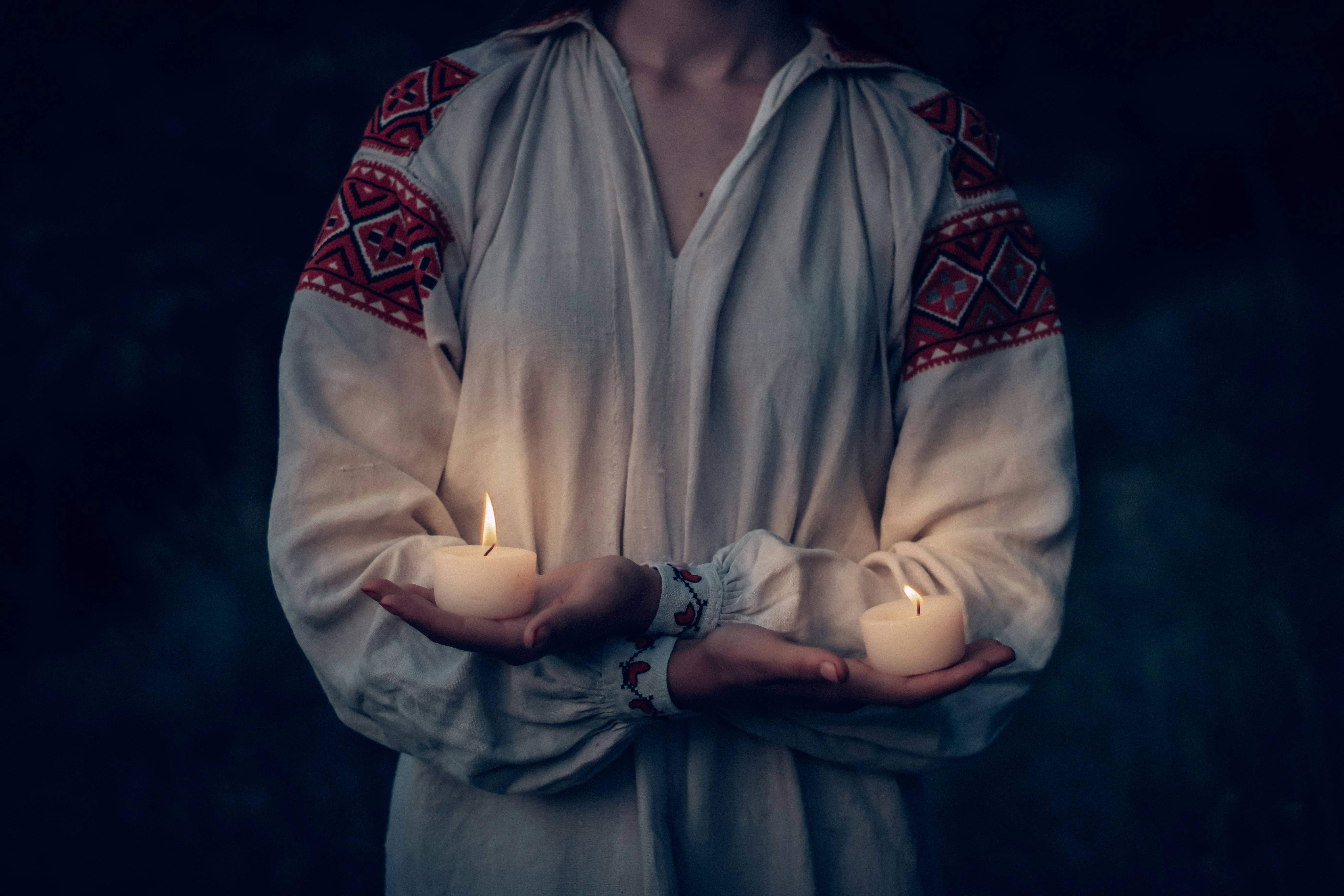 A person holds two glowing candles.