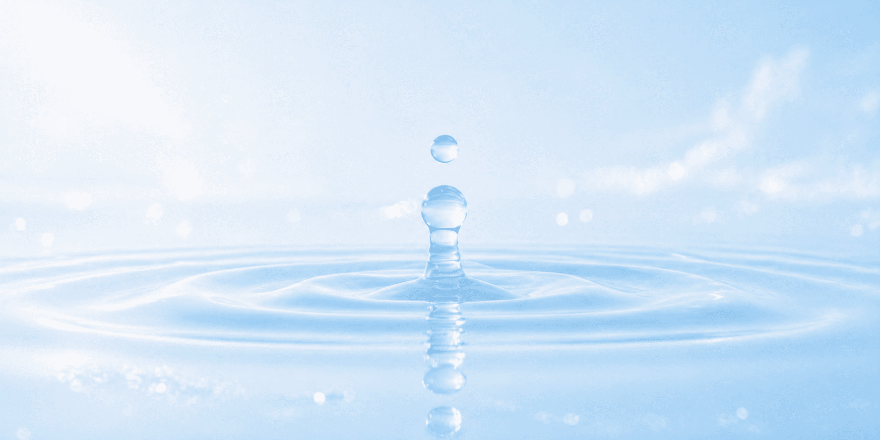 Close-up macro shot of clear water droplet splash with ripples on light blue background