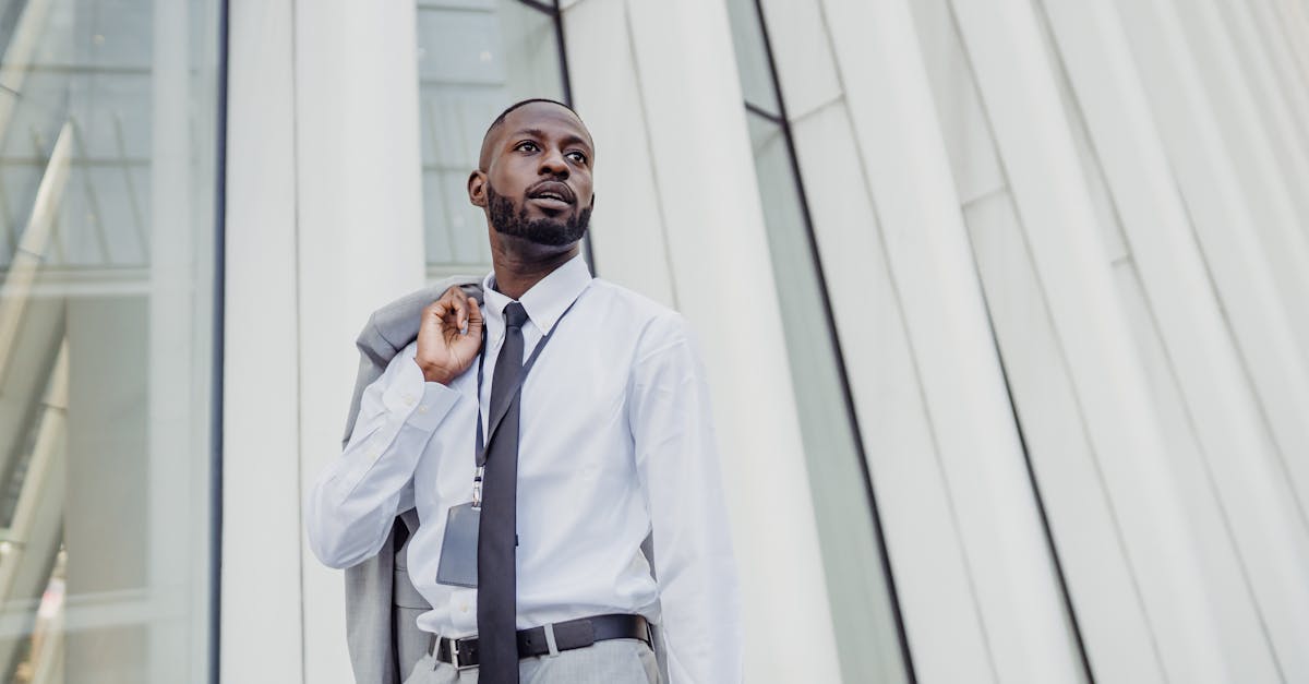 Businessman in formal attire posing in front of modern office building facade.