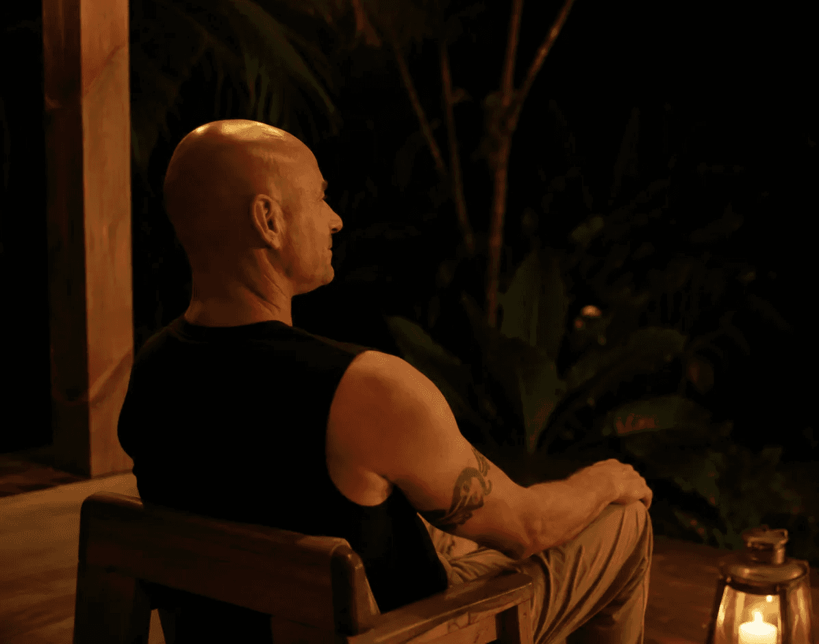 Maestro Sani seated beside a lantern overlooking the Costa Rican rainforest at night