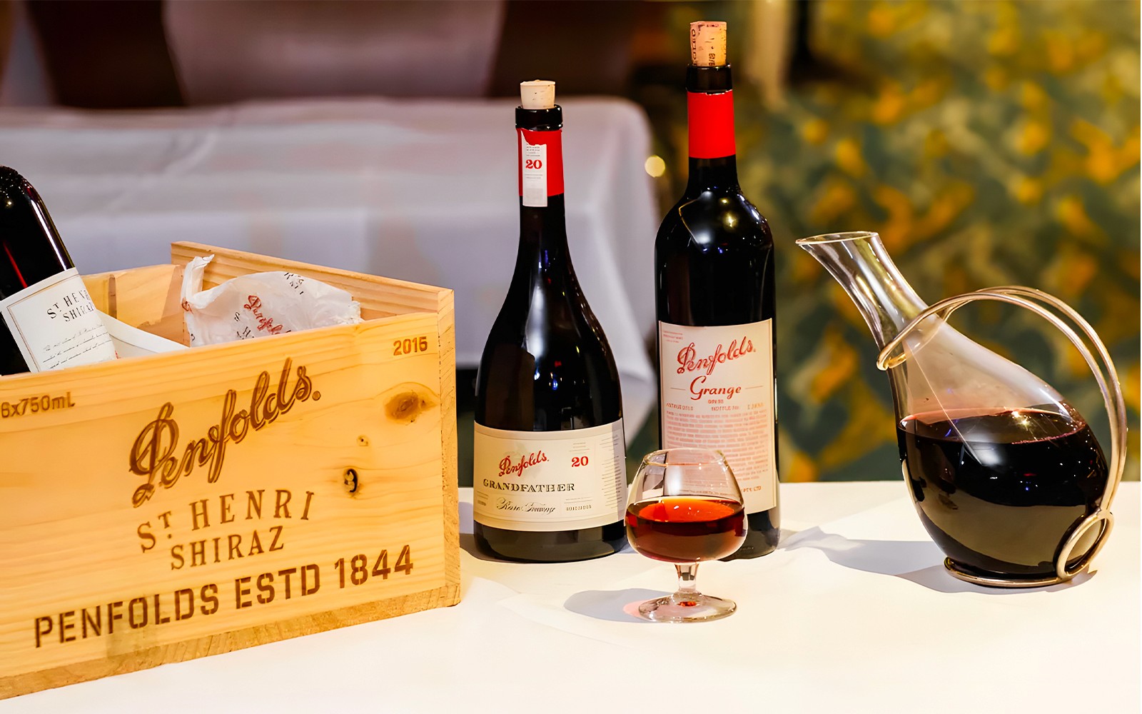 Penfolds wijnflessen en karaf met houten kist tentoongesteld.