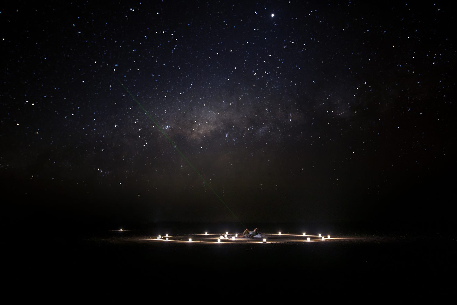 A candlelit circle on the desert floor beneath the Milky Way