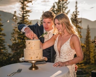 The couple cut their two-tier wedding cake outdoors beside the mountain overlook.