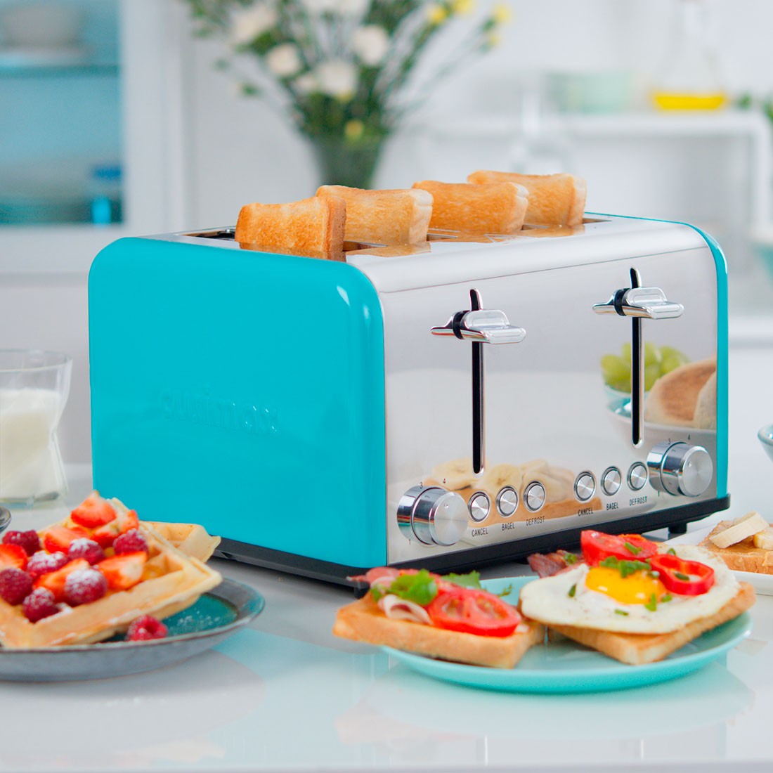 A sleek, blue stainless steel toaster with four slots is surrounded by plates of toasted bread, topped with fresh berries, avocado, and a sunny-side-up egg, placed on a modern kitchen counter with soft-focus floral decor in the background, perfect for a breakfast setup.