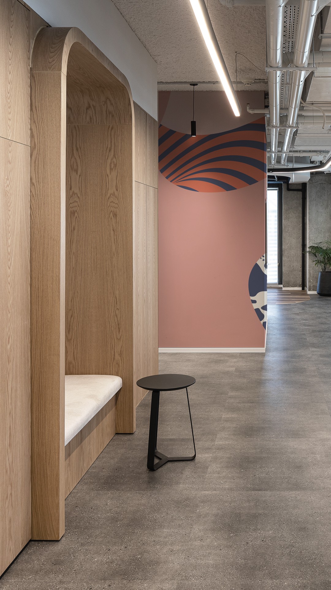 פרטיות בחלל הפתוח: נישת ישיבה אינטימית (Acoustic Booth) בחיפוי עץ אלון, המאפשרת רגע של שקט או שיחת טלפון פרטית בתוך המשרד הדינמי.