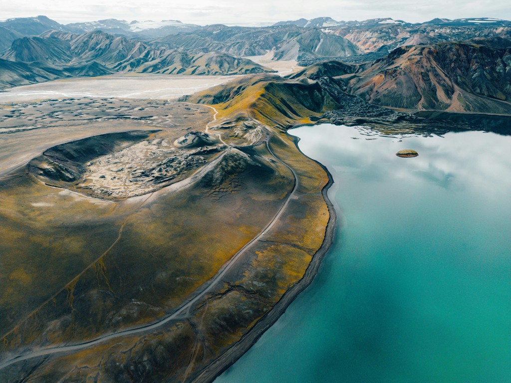 A road through hills next to a body of water as seen from above