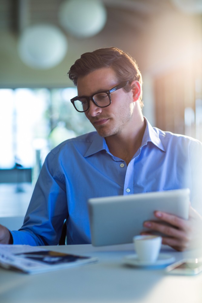 Man wearing glasses reviewing tasks on a tablet, representing checklist management and workflow compliance.
