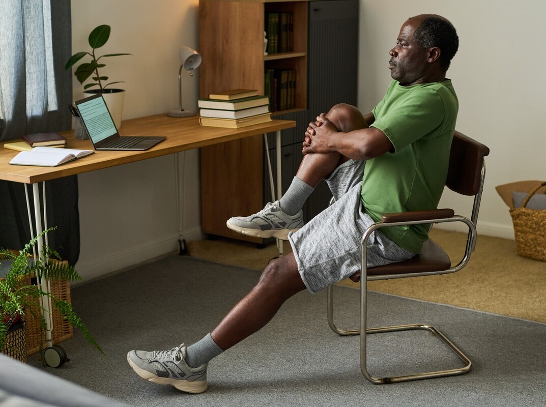 older man doing his daily chair exercises for weight loss at home during a break from work