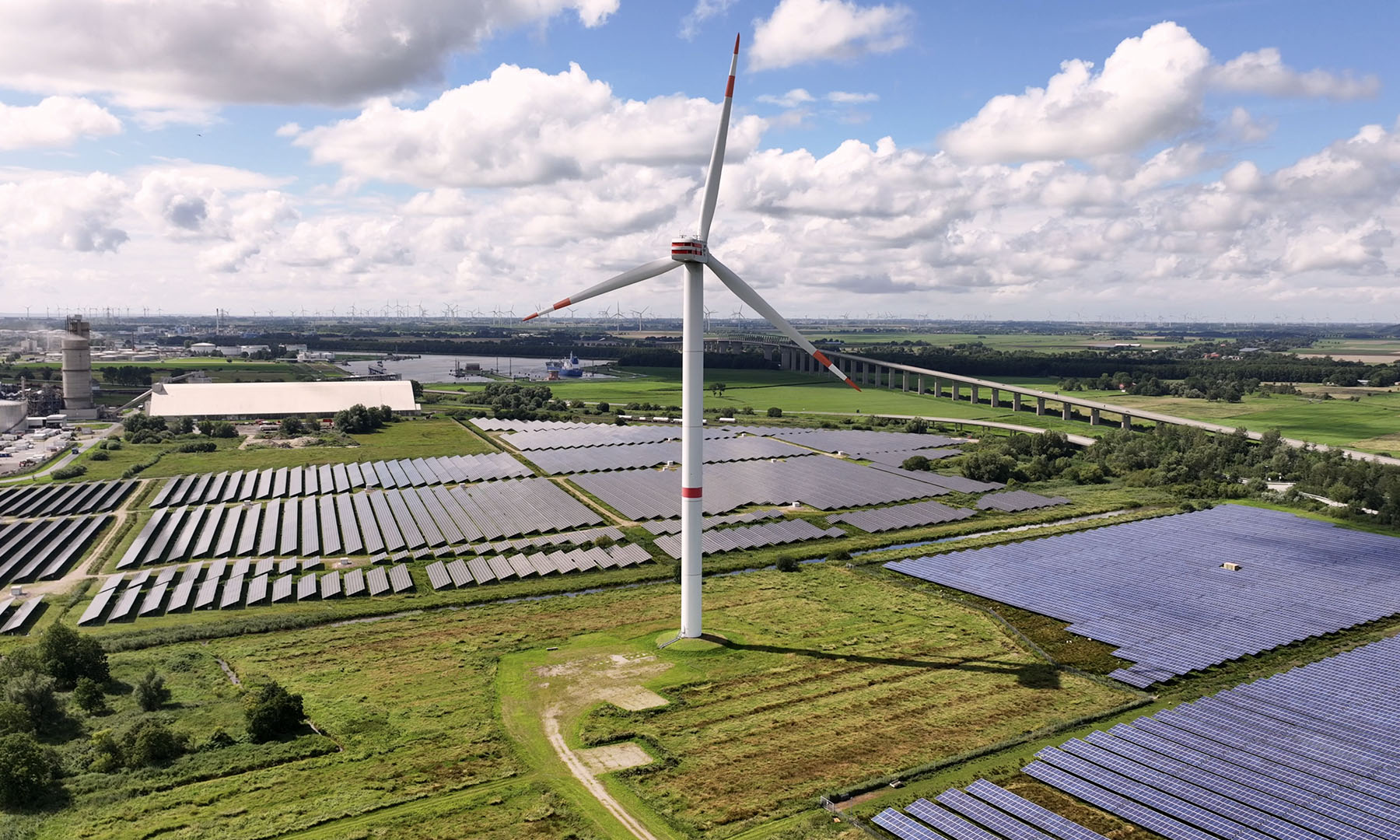 A green landscape with a wind turbine and solar panels