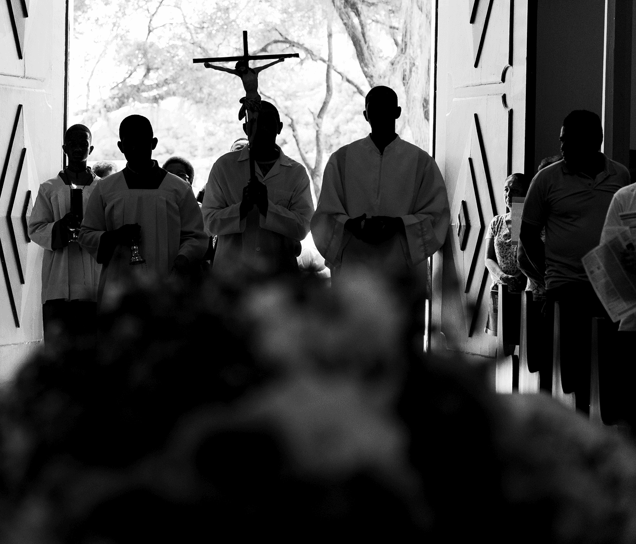 Confident male speaker in a white shirt and headset mic gesticulates on stage with teal spotlighting.