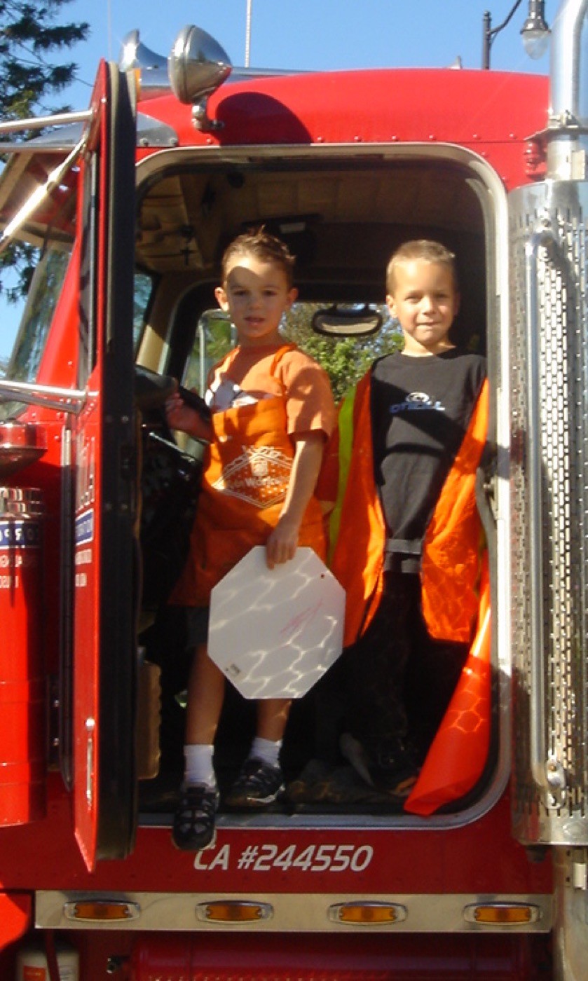 Cole and Landon as boys in safety vests standing in the cab of a semi truck, 2007