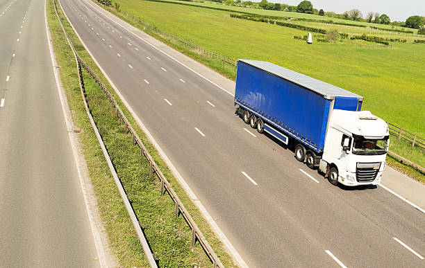 large road haulage vehicle driving down the road with a blue trailer