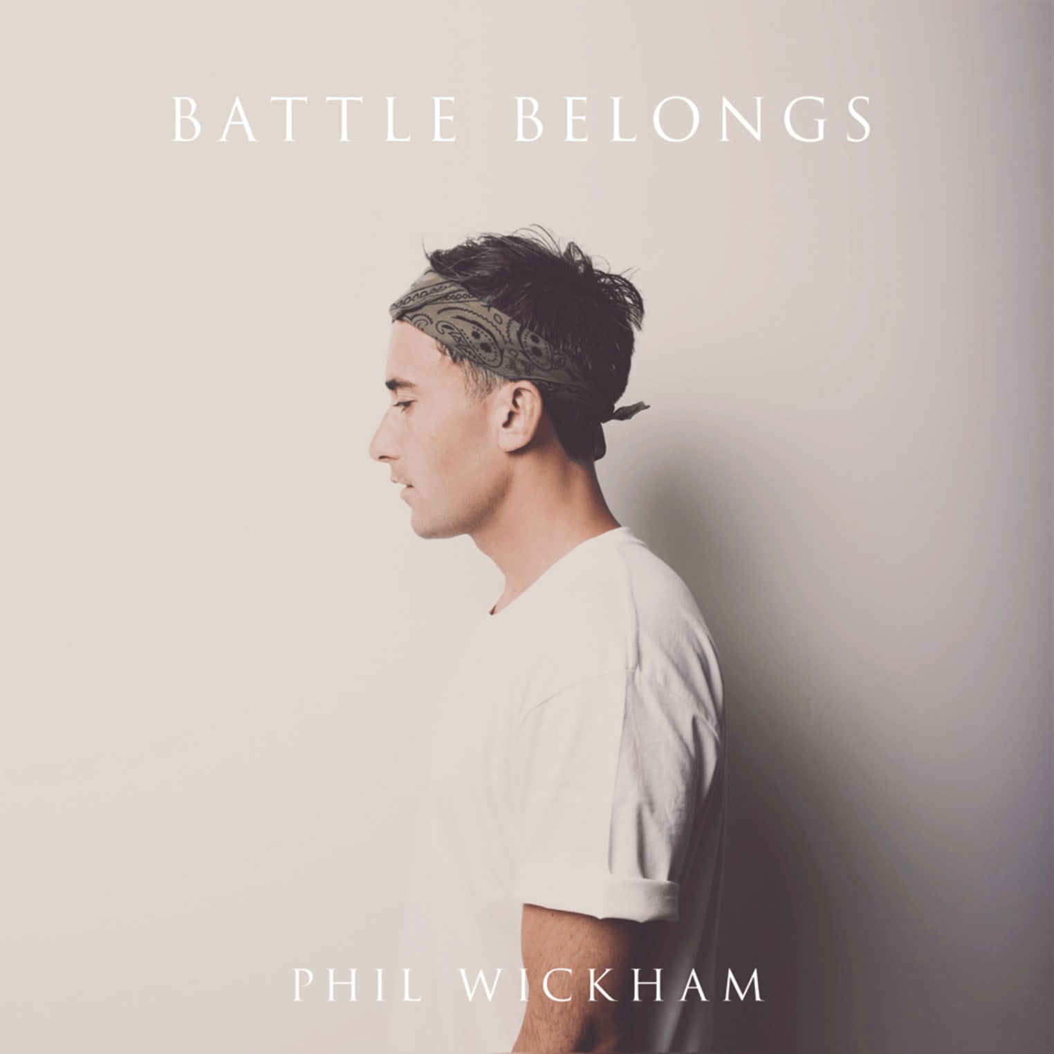 Album artwork for "Battle Belongs" by Phil Wickham: A man in profile, white shirt and headband, stands before a plain background. Title and artist shown.