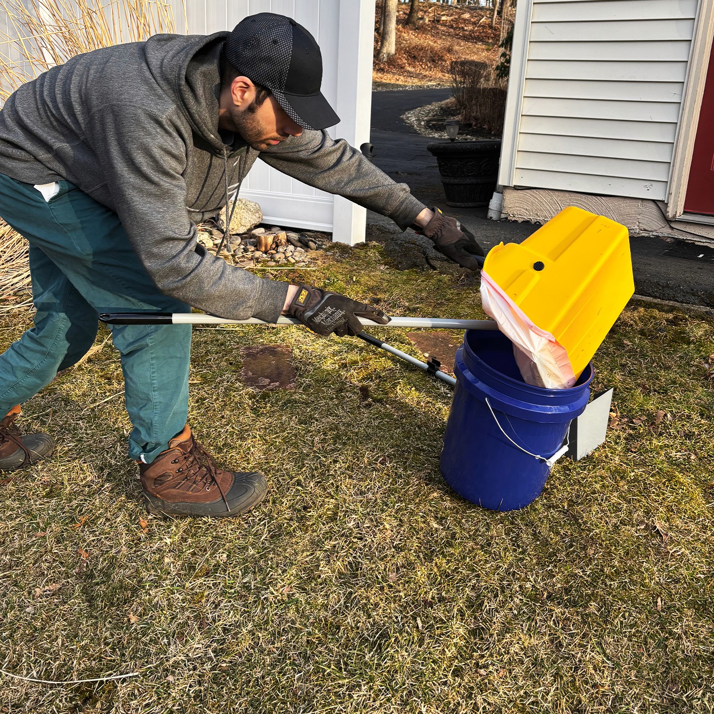 man holding trash bag scooping dog poop