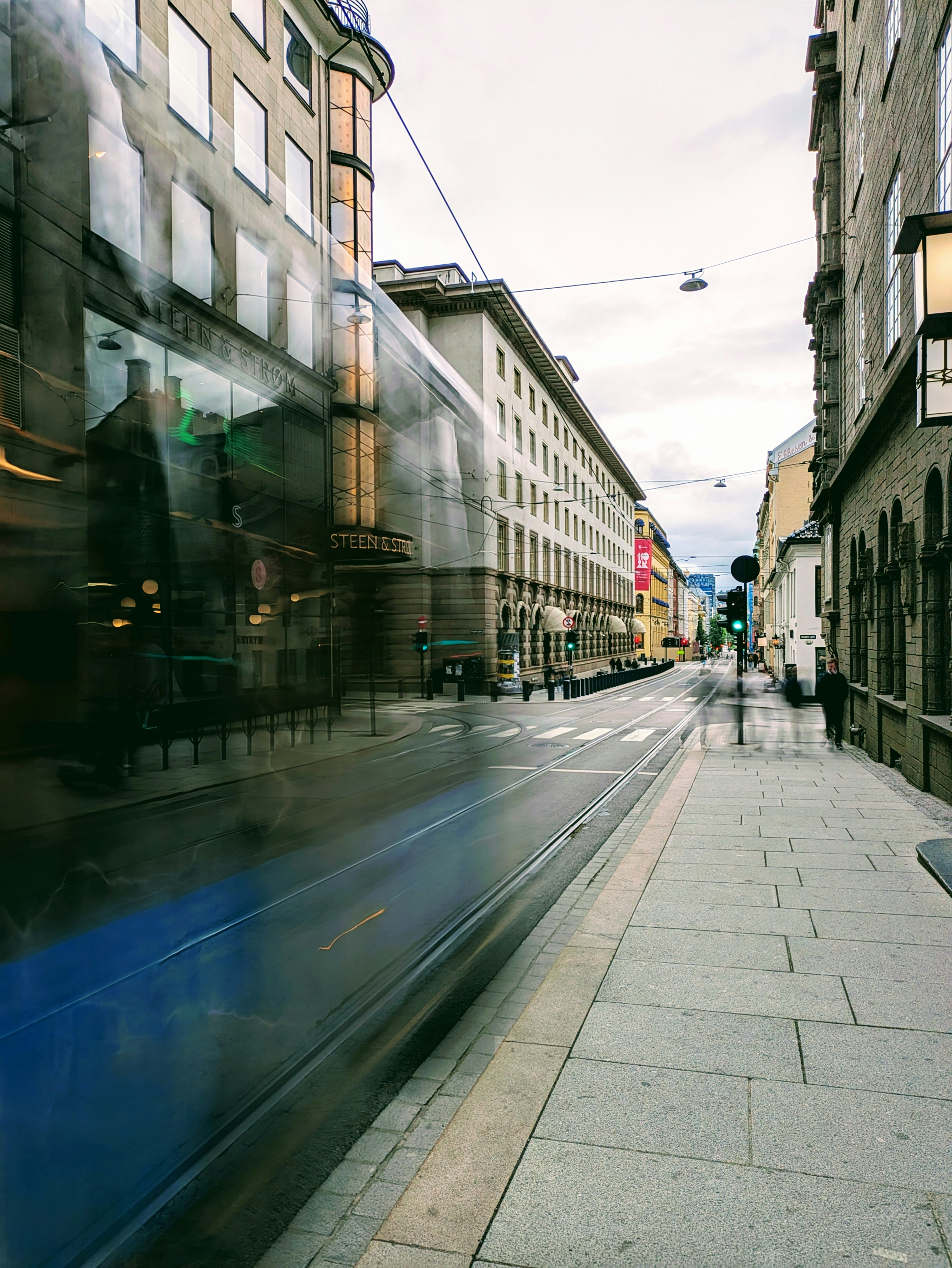 Blurred tram passing by a city street.