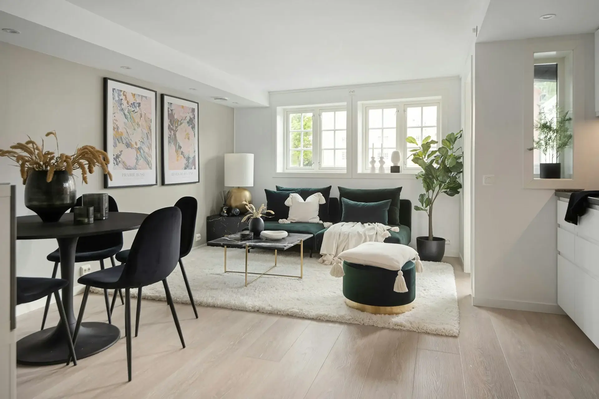 Modern living area with dark green sofa, dining table, soft lighting, and plants.