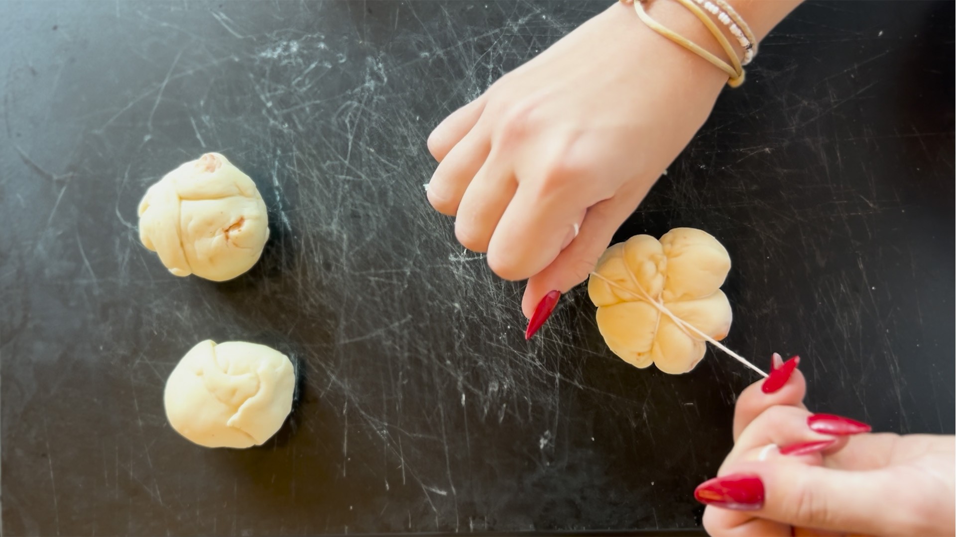 Hände formen Teig zu Kürbisbrötchen für Halloween auf einer Arbeitsfläche