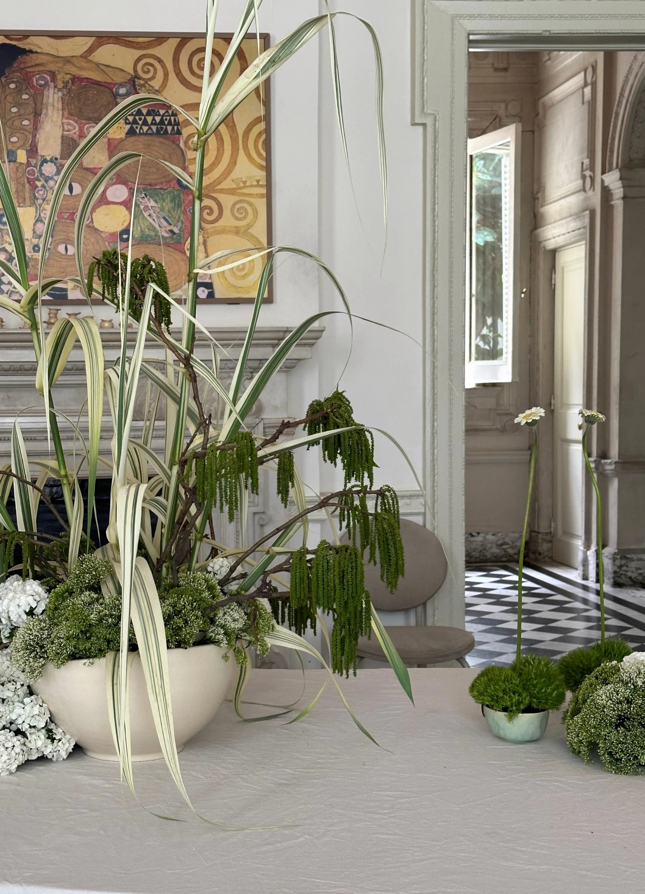 Instalación floral contemporánea con flores rojas y fucsias sobre mesas blancas.