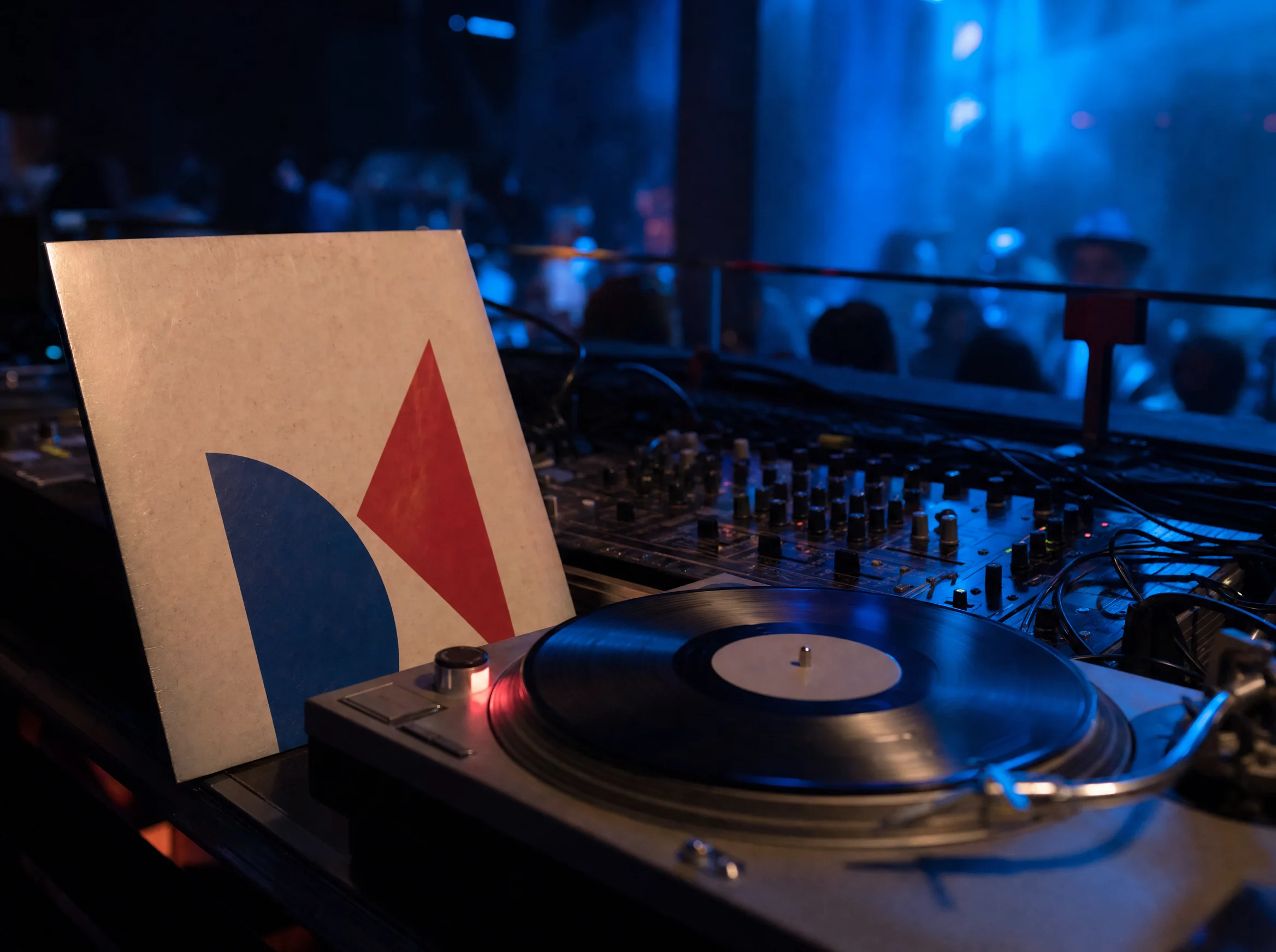 Nachtvlinder sleeve leaning on a mixer in a dark club
