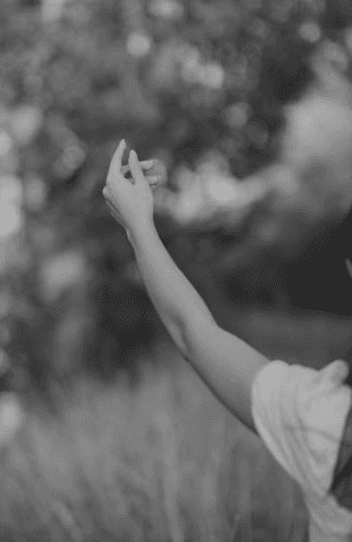 A circle of people sitting cross-legged, meditating with hands in a prayer position. Soft, warm lighting.