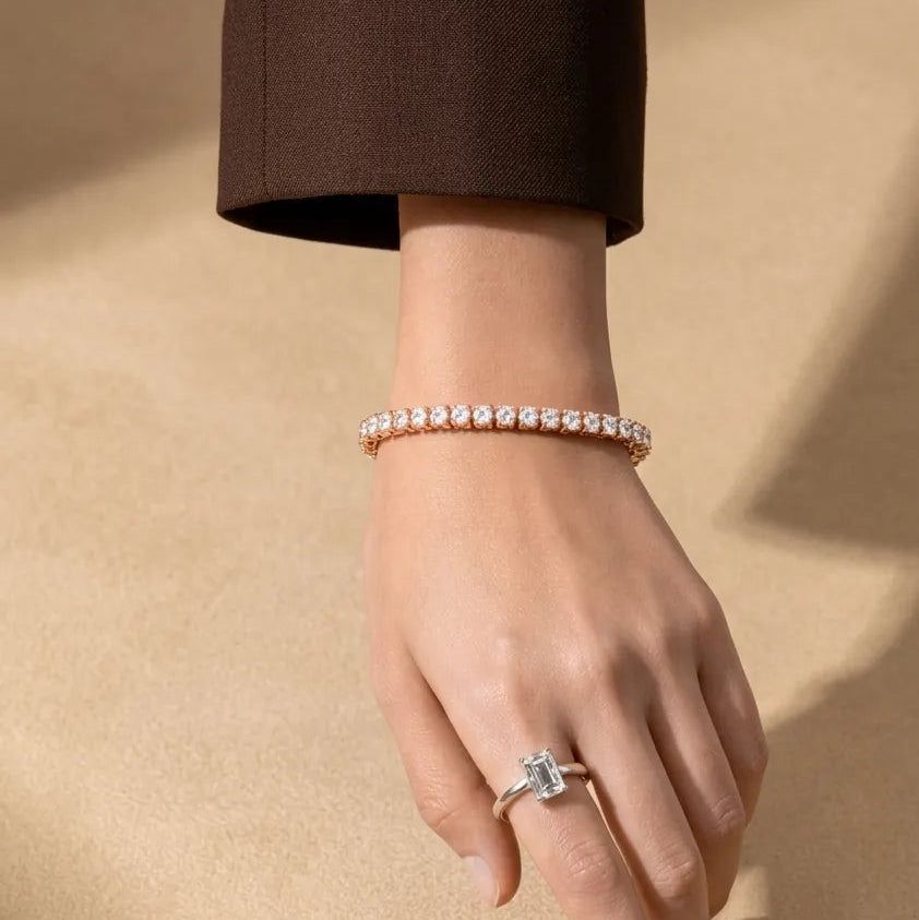 Hand wearing a diamond ring and bracelet on a beige background