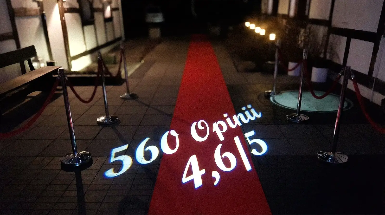 Czerwony dywan przed wejściem do sali weselnej Wrzosowy Tartak, z projekcją świetlną przedstawiającą ocenę 4,6/5 na podstawie 560 opinii.