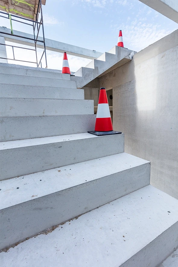 Stairs lacking a handrail with traffic cones placed as warnings, representing premises liability hazards in slip-and-fall cases