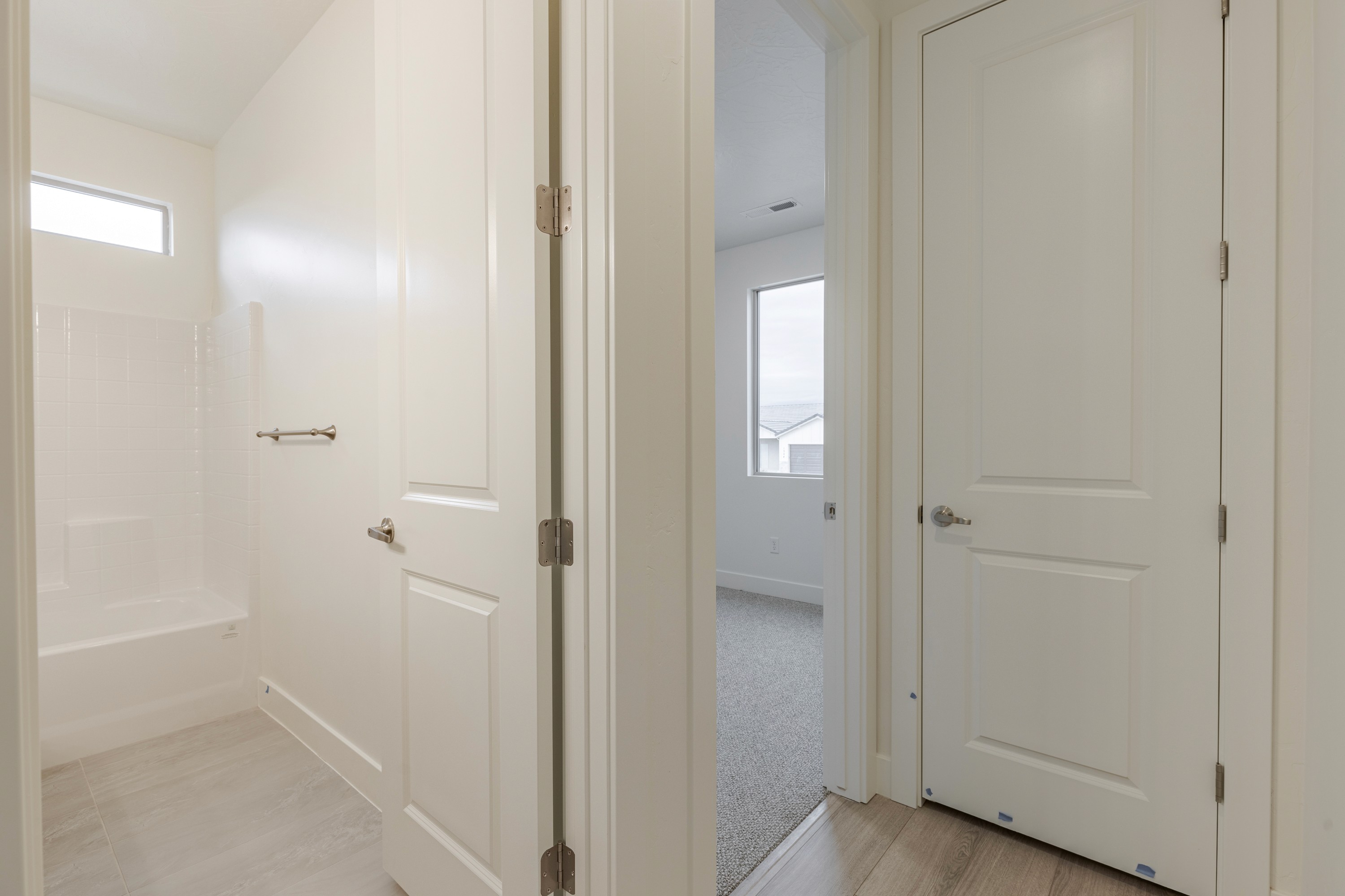 View looking from a hallway into a bedroom and secondary bathroom in the Painted Sands twin home in Hurricane, Utah showing functional layout.